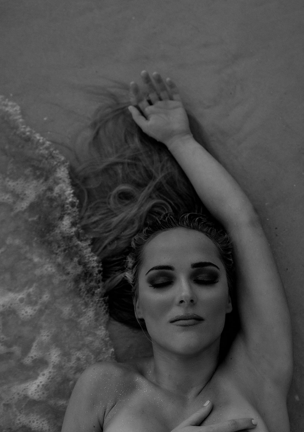Naples Boudoir Photographer, woman laying in the sand with her hand above her head