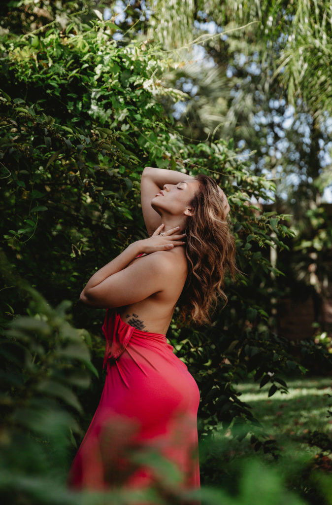 Naples Florida Boudoir Photographer, woman in red dress standing next to a large bush