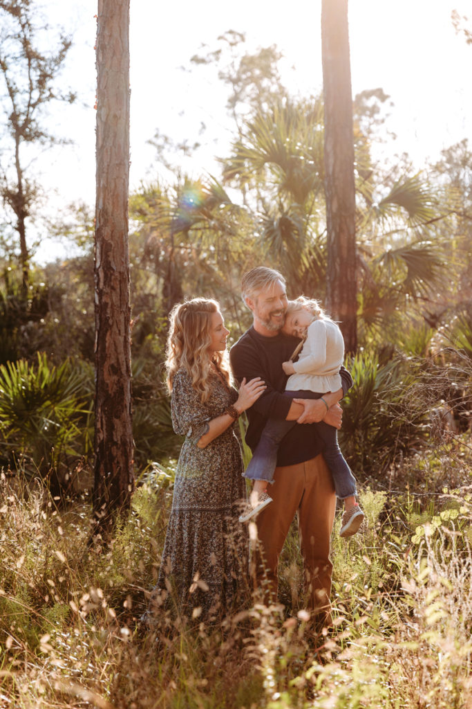 Wedding Photographer, Husband and wife hold their child while in tall dry grass